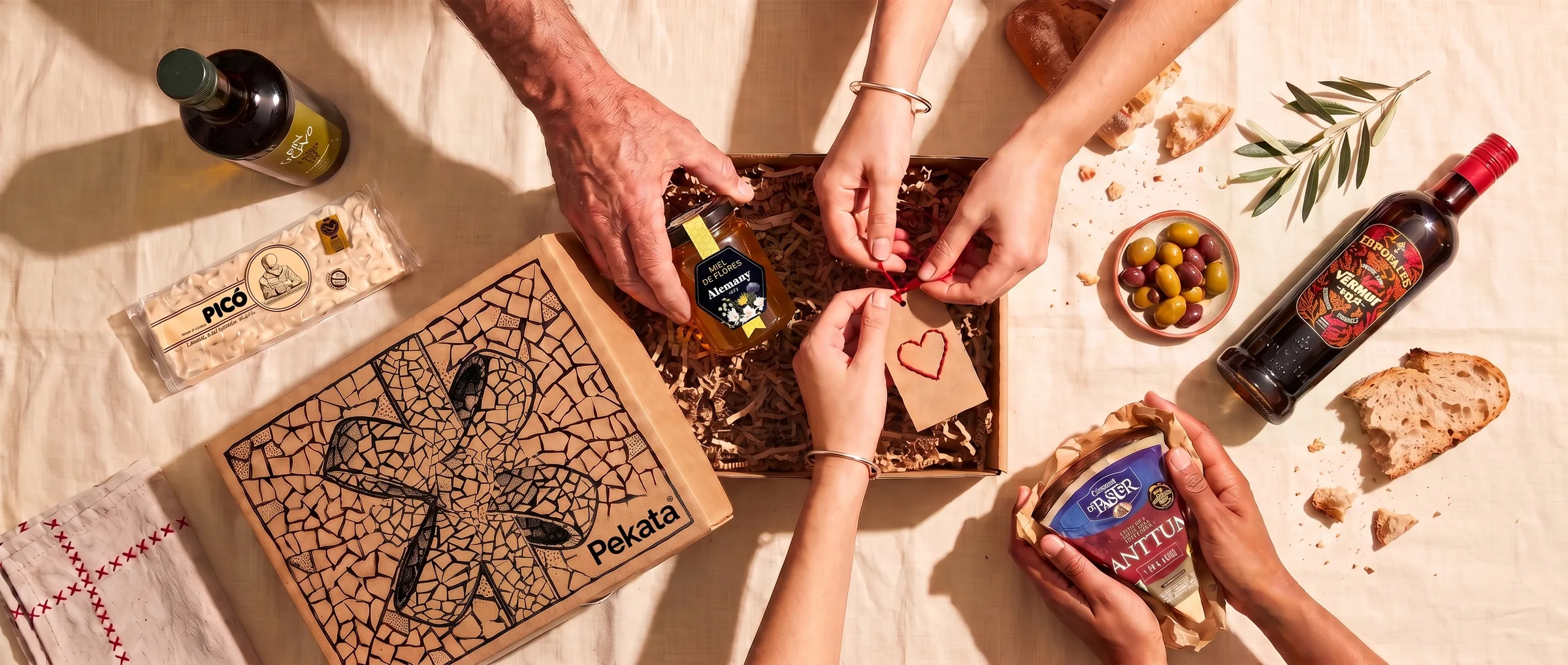 Several people's hands packing a Pekata box with a kraft tag with a stitched heart